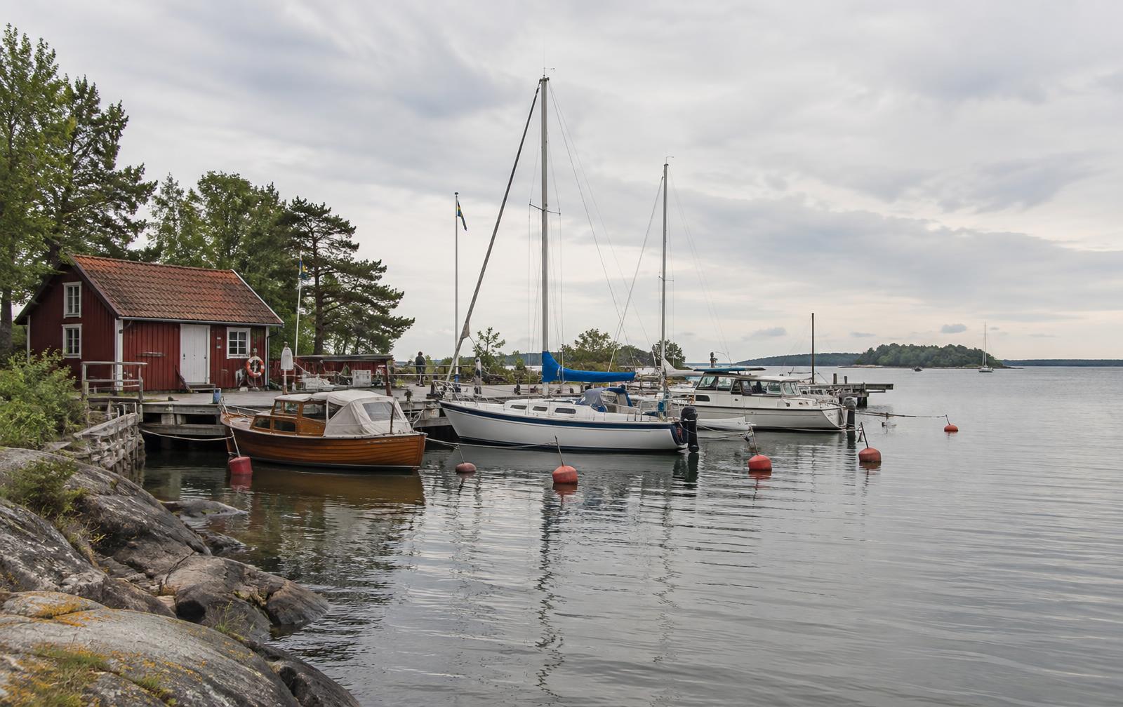 Svensk båtklubbshamn med träbryggor, klubbhus och små båtar