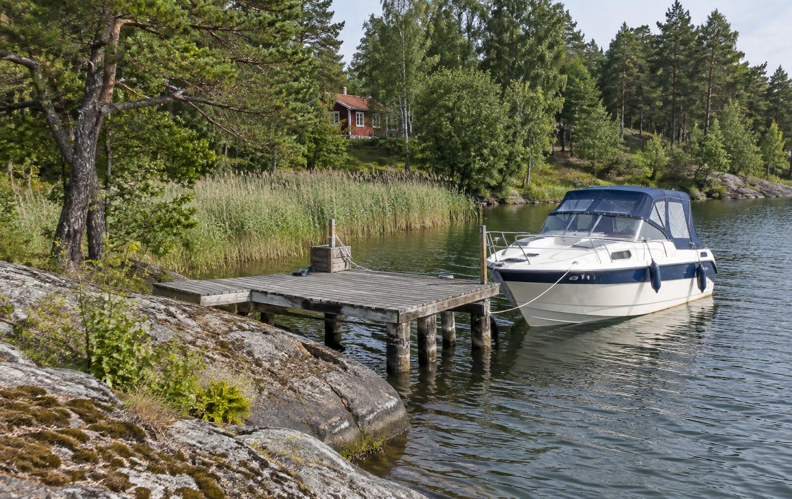 Privat träbrygga vid en stilla svensk strand i kvällsljus
